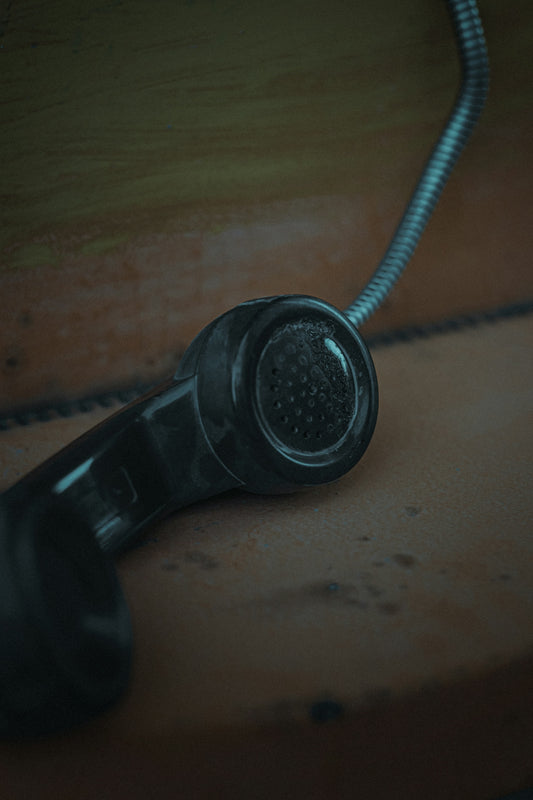 black corded telephone on brown wooden table
